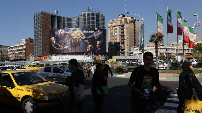 Iranians walk next to a billboard on a street in Tehran