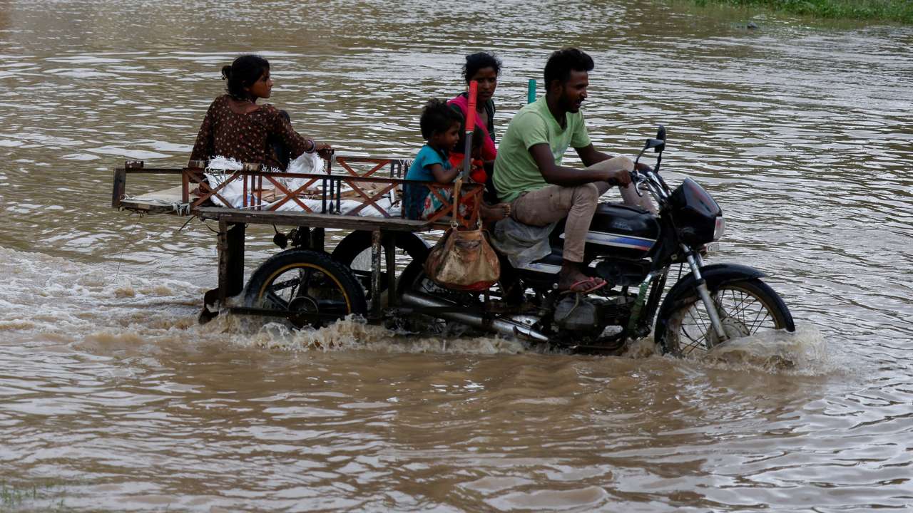 A family crosses a flooded street after heavy rains in Ahmedabad