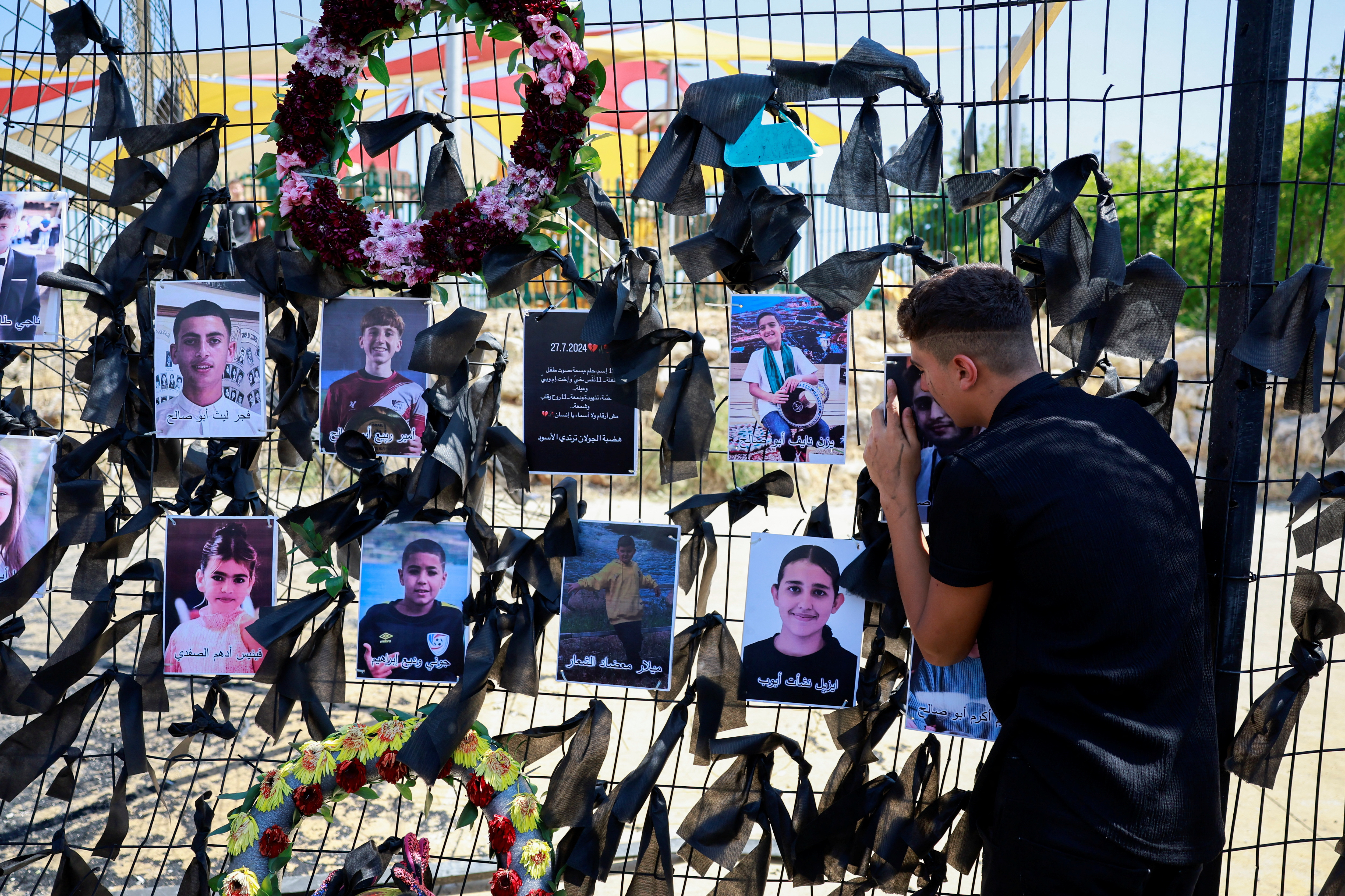 A person mourns as he embraces the picture of his loved one killed at a soccer pitch by a rocket Israel says was fired from Lebanon, in Majdal Shams