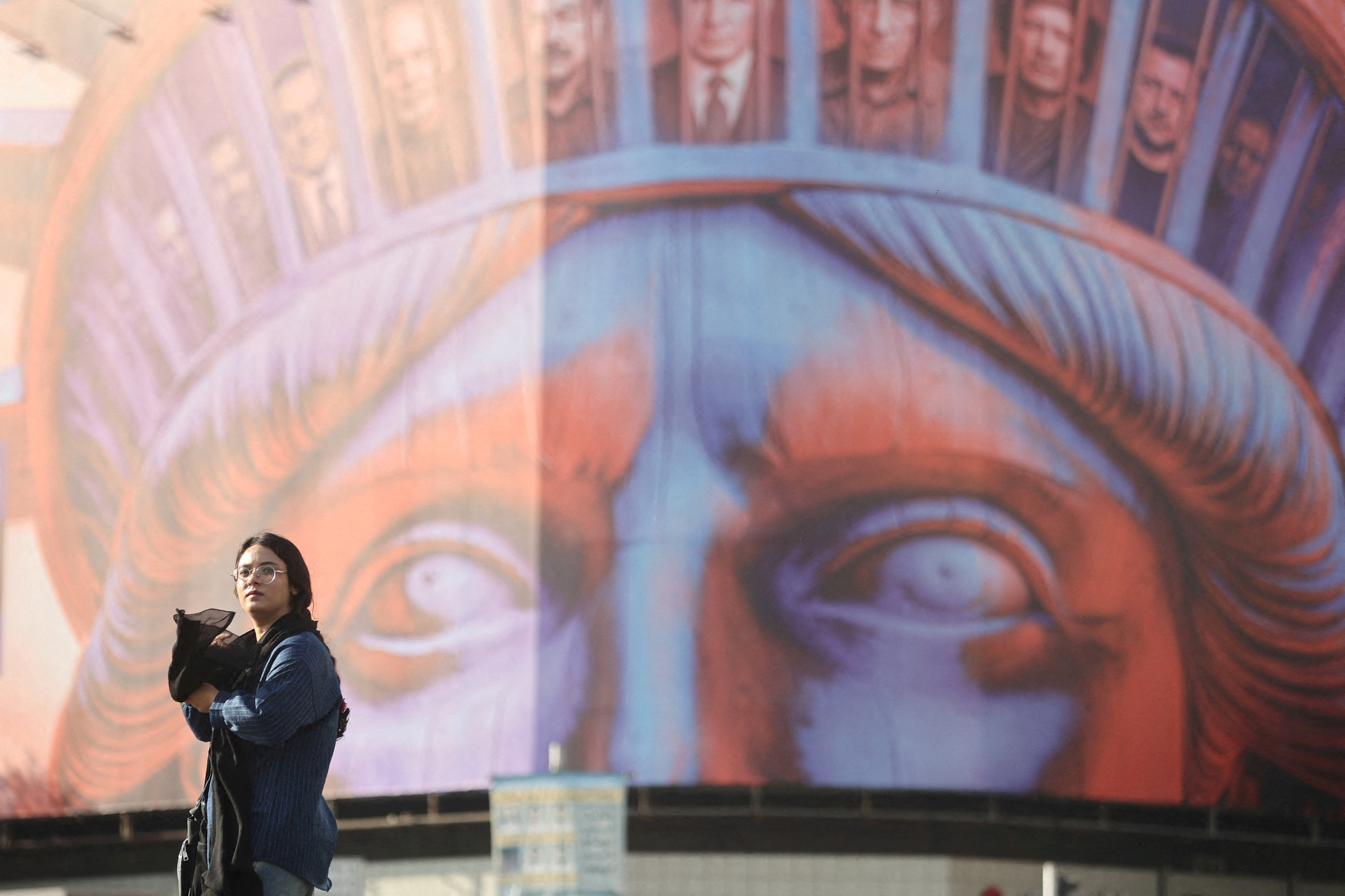 FILE PHOTO: An Iranian woman walks past an anti-U.S. billboard on a street in Tehran,