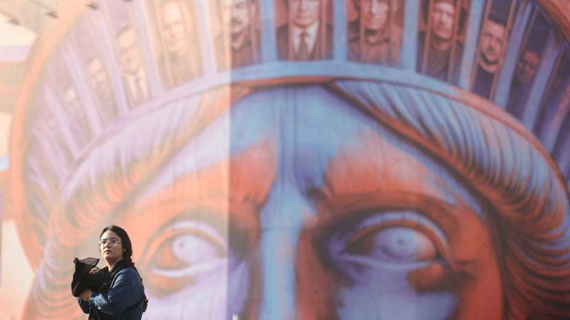 FILE PHOTO: An Iranian woman walks past an anti-U.S. billboard on a street in Tehran,