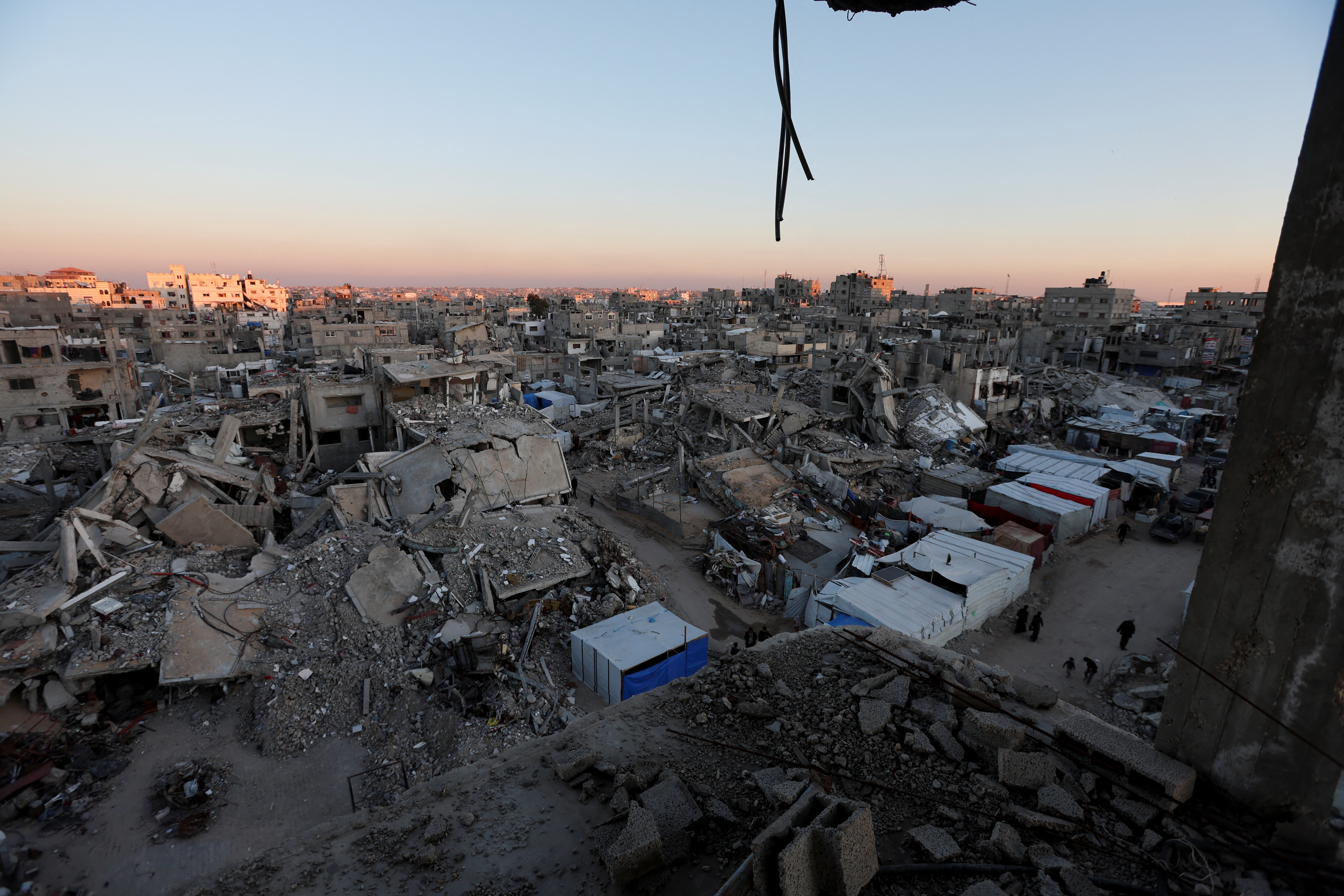 Palestinians walk near the rubble of buildings, In Khan Younis