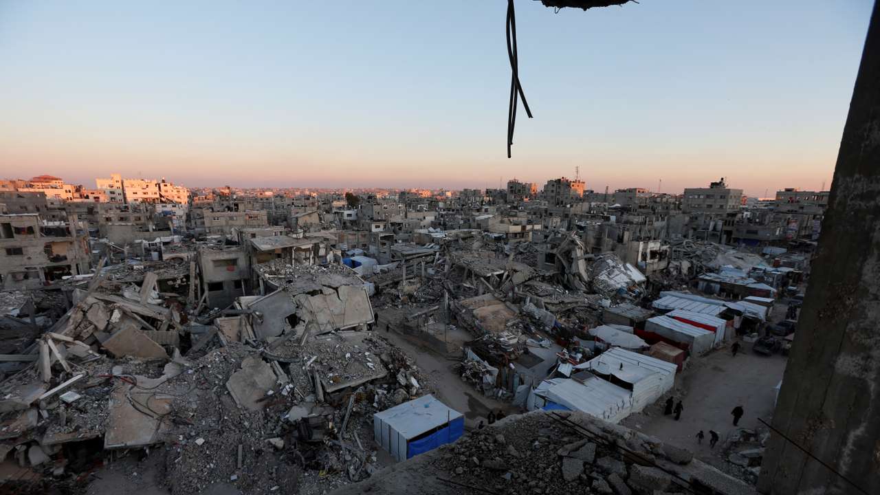 Palestinians walk near the rubble of buildings, In Khan Younis