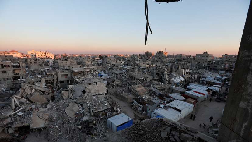 Palestinians walk near the rubble of buildings, In Khan Younis