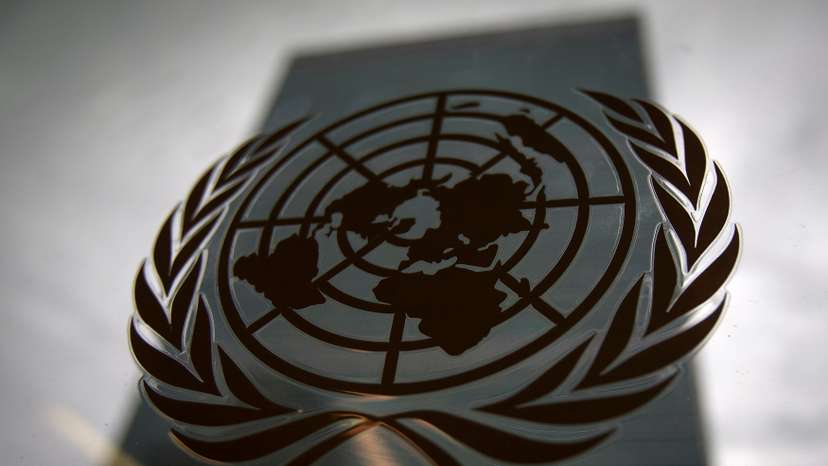 The United Nations headquarters building is pictured though a window with the UN logo in the foreground in the Manhattan borough of New York