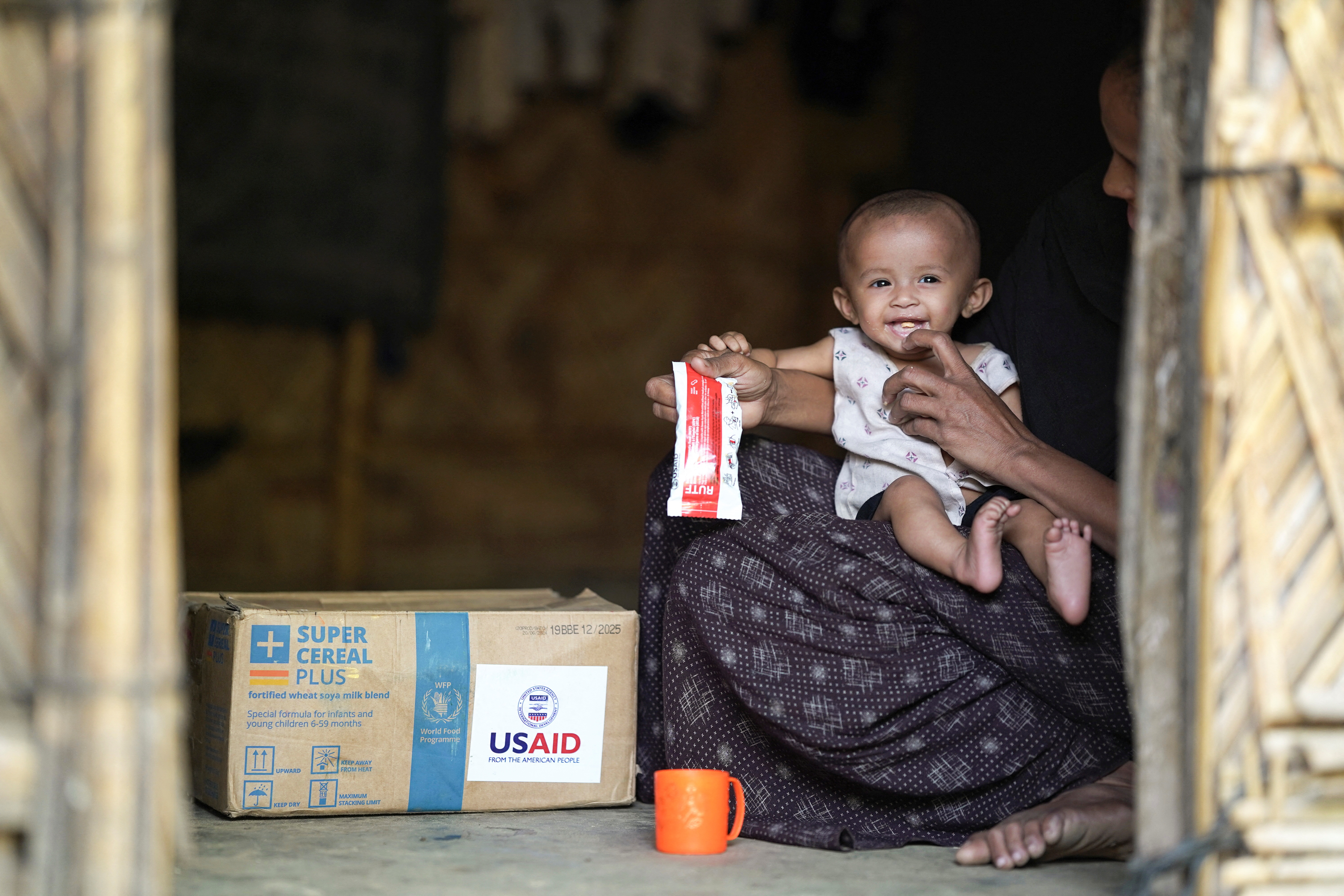 A Rohingya woman feeds nutrition supplements that have been provided by USAID, to a child at a refugee camp in Cox's Bazar