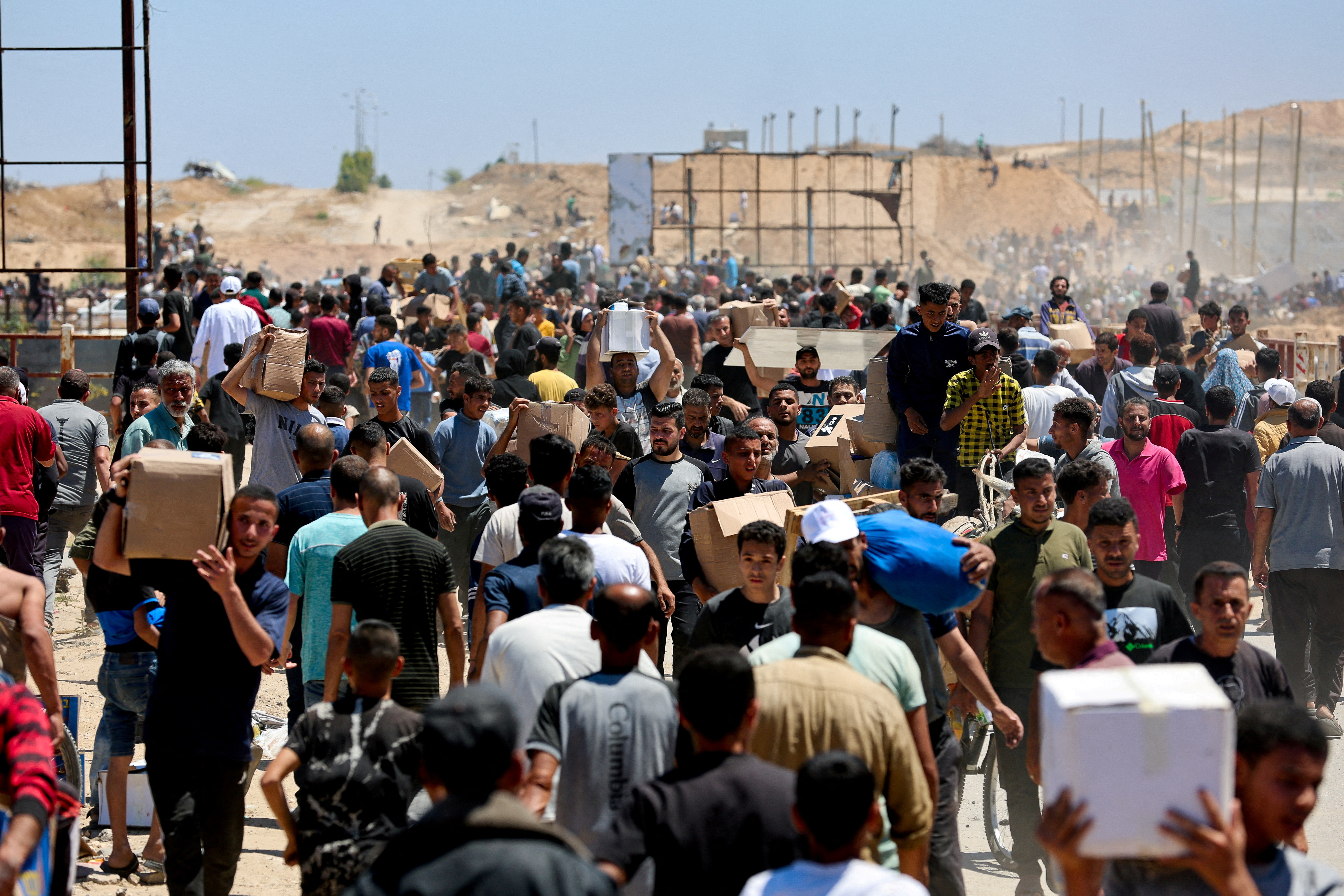 FILE PHOTO: Palestinians carry aid supplies which they received from the U.S.-backed Gaza Humanitarian Foundation