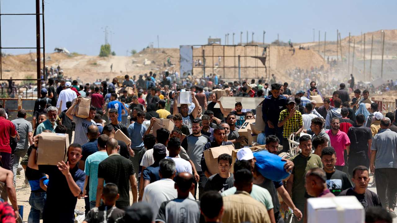 FILE PHOTO: Palestinians carry aid supplies which they received from the U.S.-backed Gaza Humanitarian Foundation