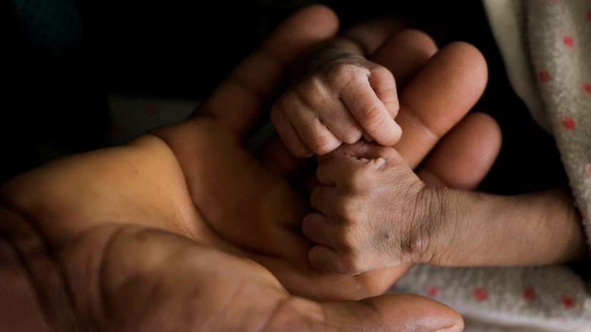 Woldegebrial Abadi, 36, holds the hands of his severely malnourished newborn son Berhanu Woldegebrial at the Samre Hospital, in Tigray Region