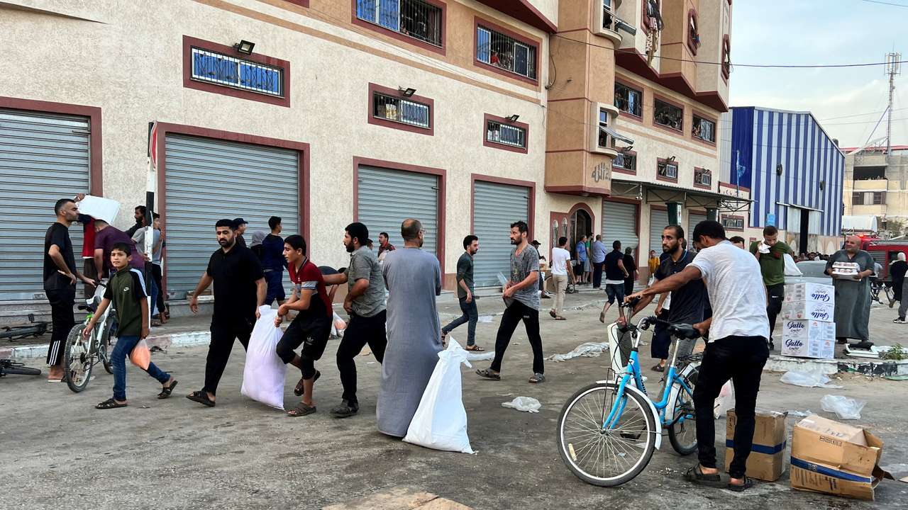 Palestinians carry food supplies near a United Nations Palestinian refugee agency (UNRWA) run warehouse in Khan Younis