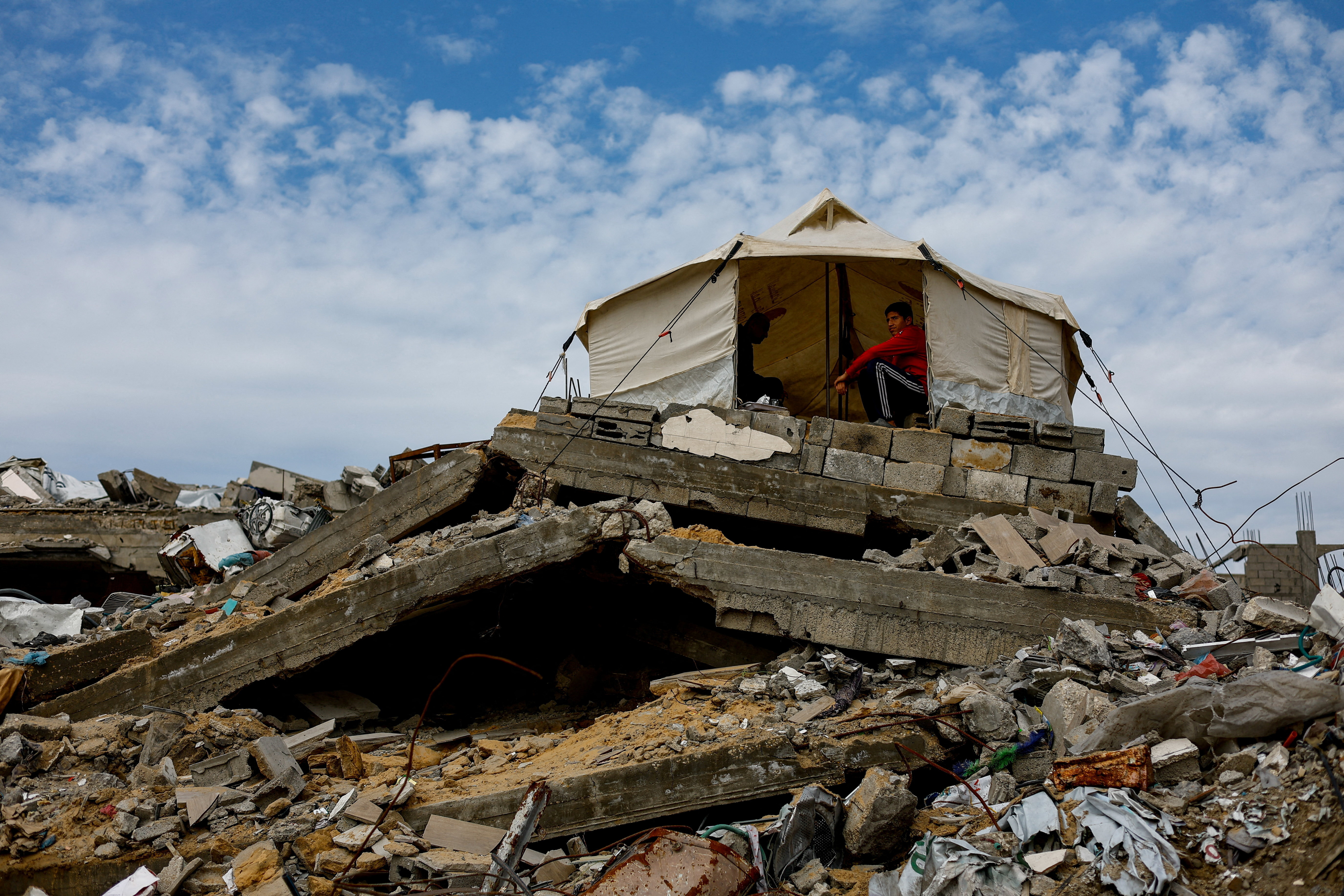 Palestinians gather in a tent that is placed on top of the rubble of buildings destroyed during the war, in Jabalia