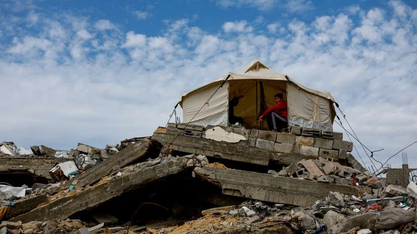 Palestinians gather in a tent that is placed on top of the rubble of buildings destroyed during the war, in Jabalia