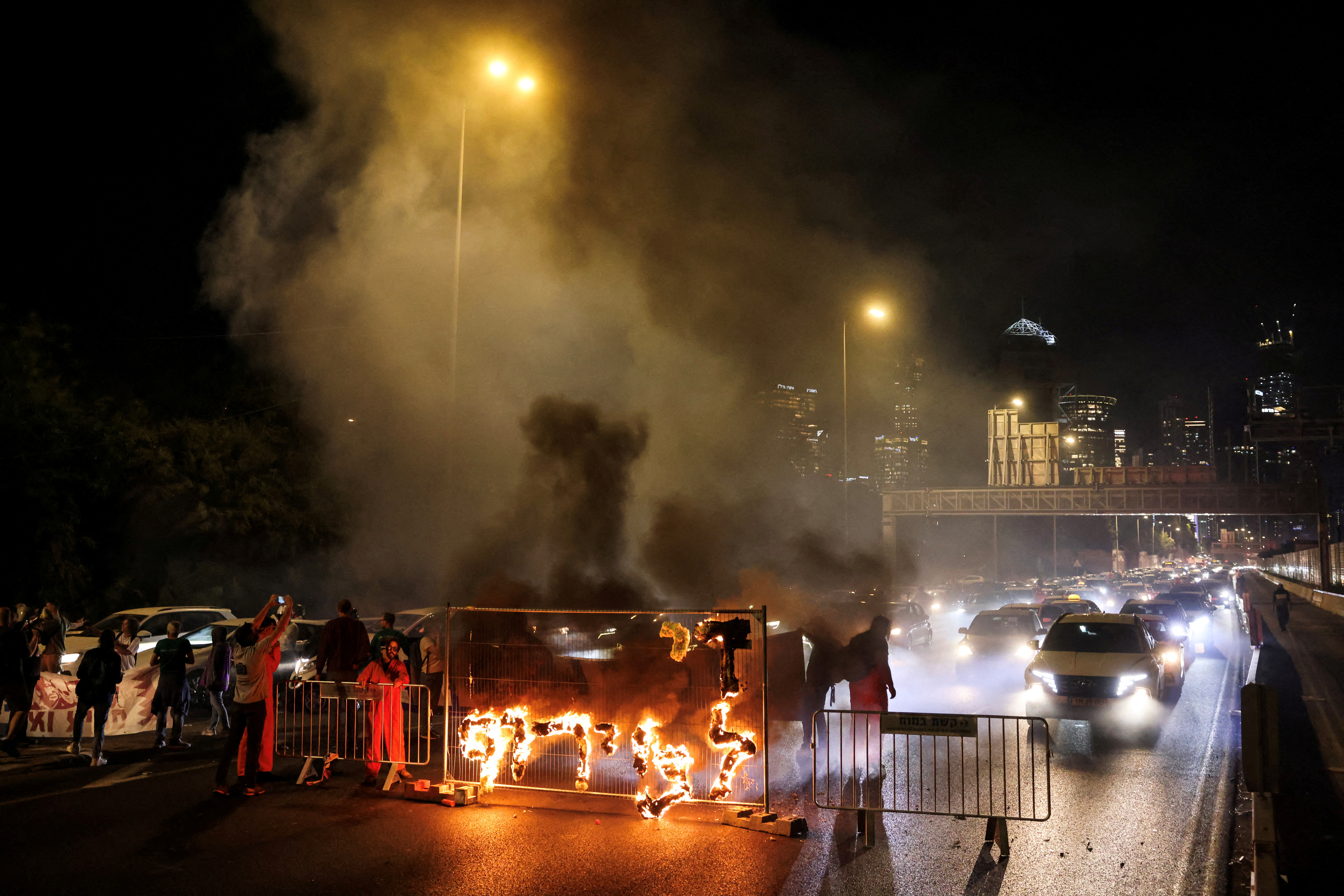 Fire blazes with the words in Hebrew, "Enough with the madness", calling for Gaza hostages release, in Tel Aviv Israel