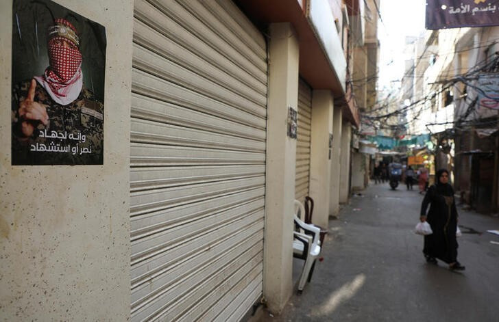 A woman walks past shops closed in response to the global call for a strike in solidarity with Gaza and Palestinian people, at Burj al-Barajneh refugee camp in Beirut
