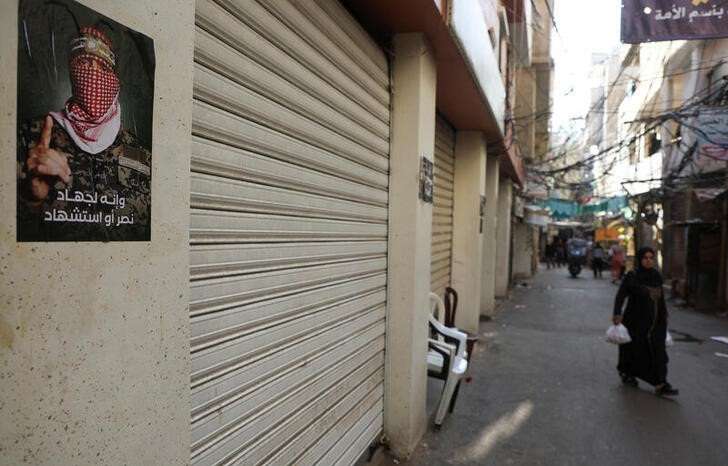 A woman walks past shops closed in response to the global call for a strike in solidarity with Gaza and Palestinian people, at Burj al-Barajneh refugee camp in Beirut