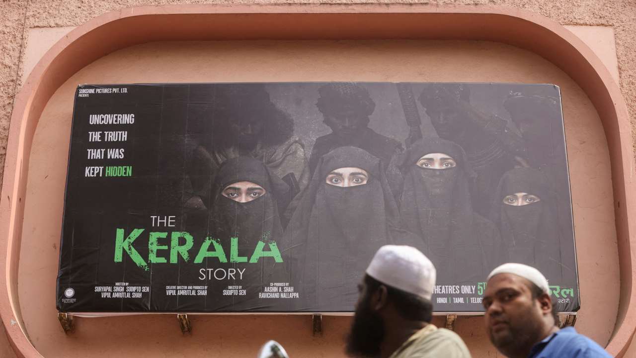 FILE PHOTO: People ride past a poster of a Hindi movie titled "The Kerala Story", outside a cinema in Mumbai