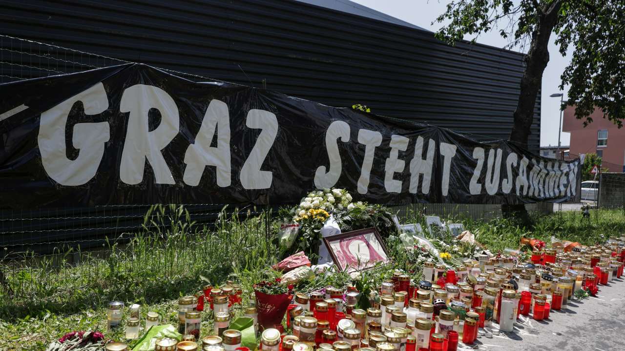 Flowers and candles are seen in front of the fences of the school in Graz