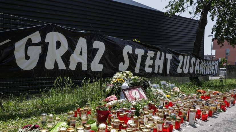 Flowers and candles are seen in front of the fences of the school in Graz