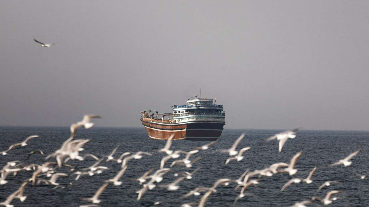 Birds fly near a boat in the Strait of Hormuz amid the U.S.-Israeli conflict with Iran, as seen from Musandam