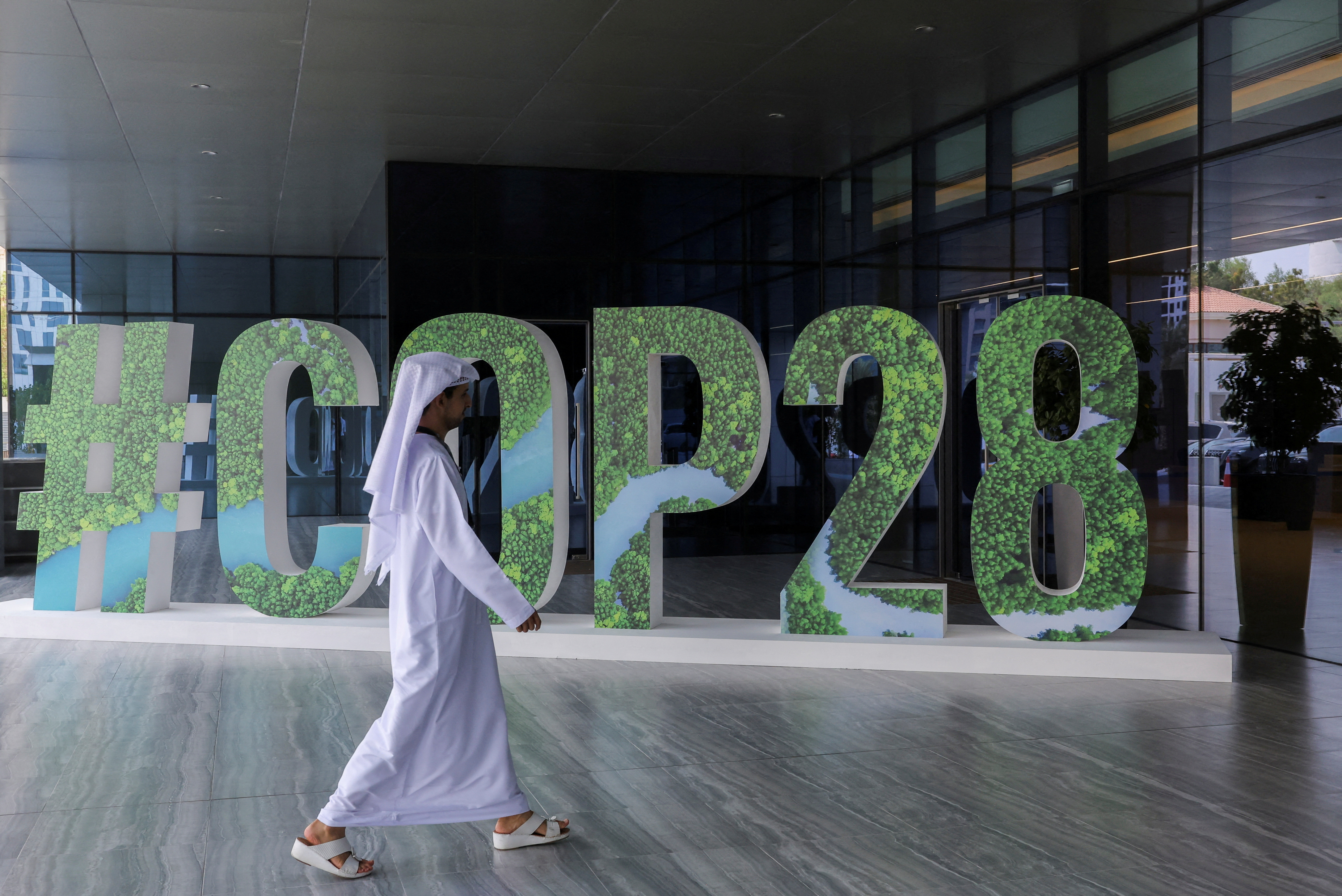 FILE PHOTO: A person walks past a "#COP28" sign during The Changemaker Majlis, a one-day CEO-level thought leadership workshop focused on climate action, in Abu Dhabi