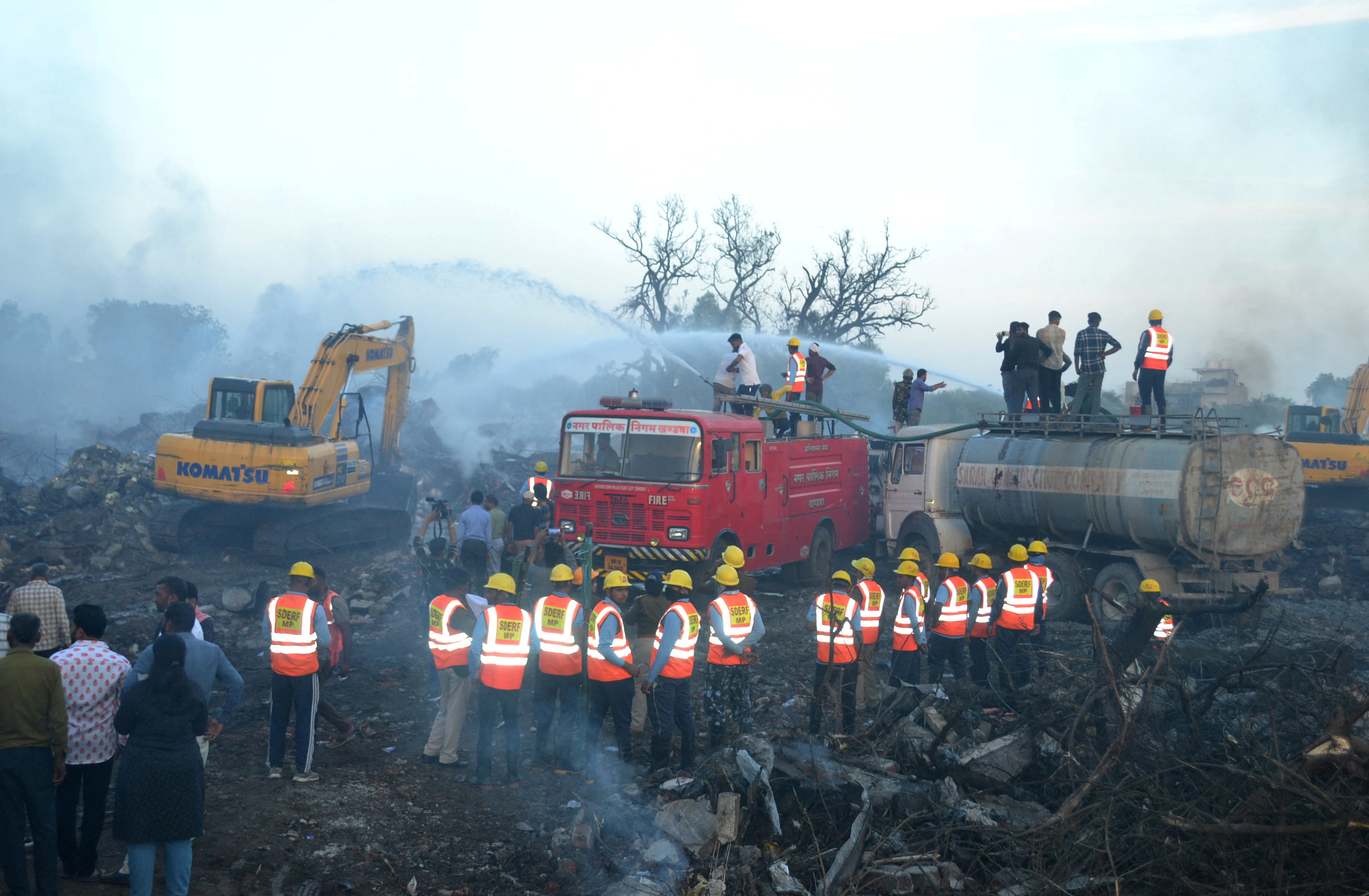 Rescue members from SDRF douse smoldering debris following a blast in a firecracker factory in Harda
