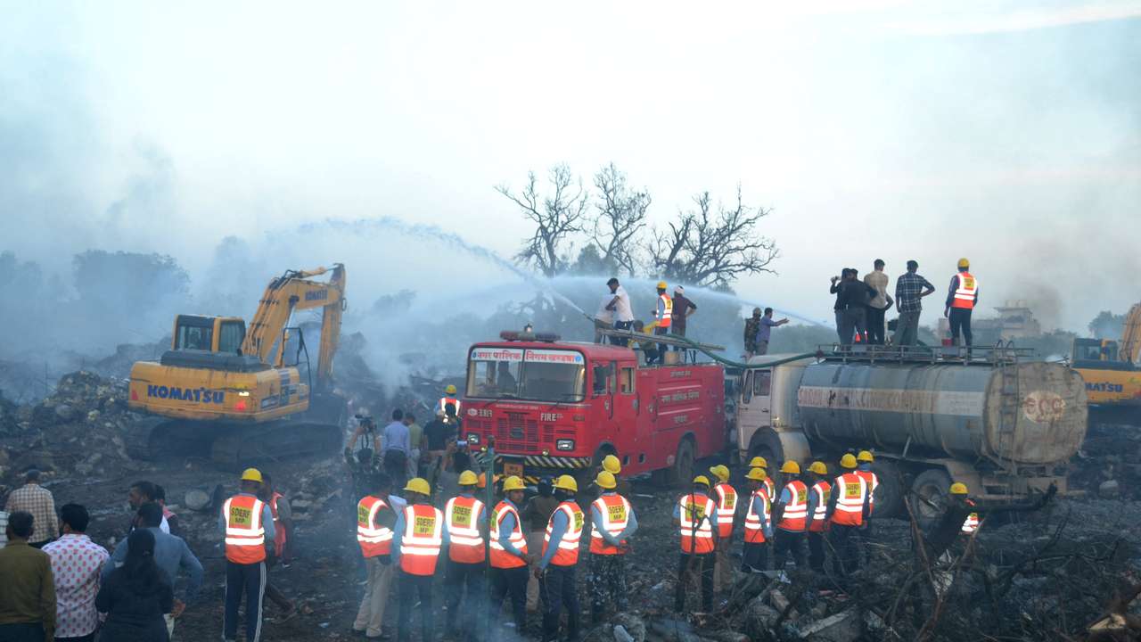 Rescue members from SDRF douse smoldering debris following a blast in a firecracker factory in Harda