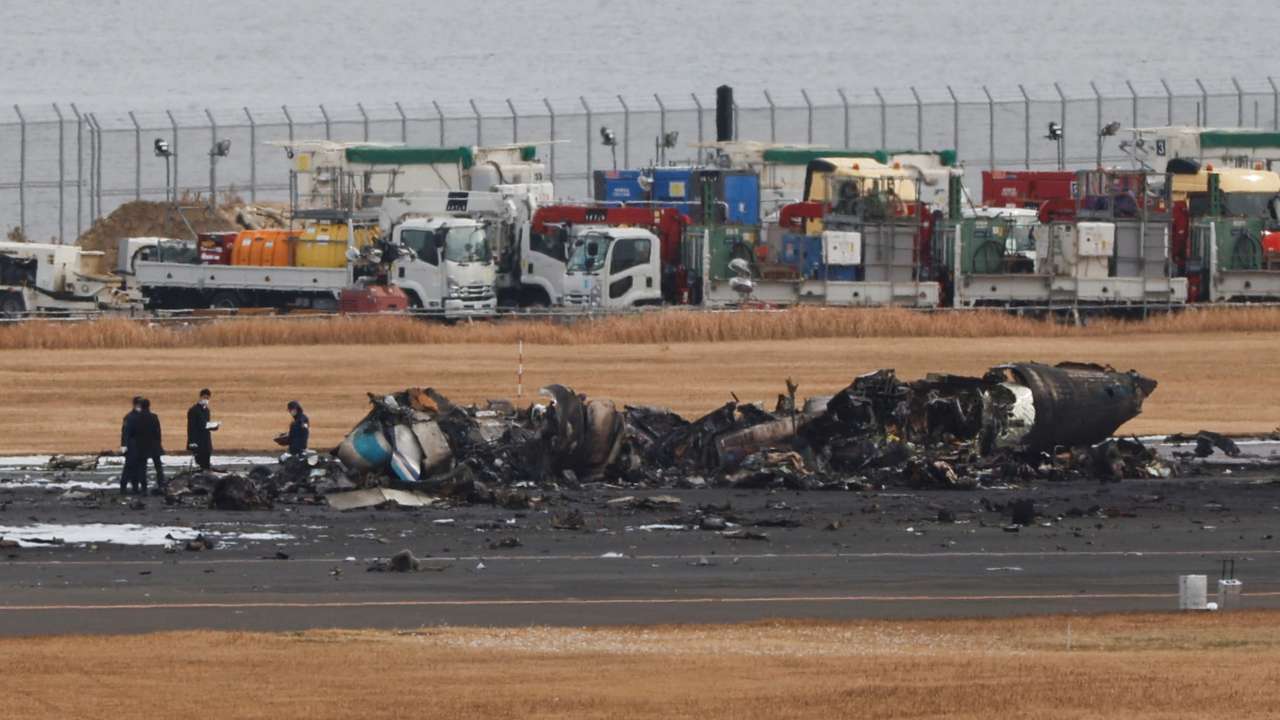 Officials investigate a burnt Japan Coast Guard aircraft after a collision with Japan Airlines' (JAL) Airbus A350 plane in Tokyo
