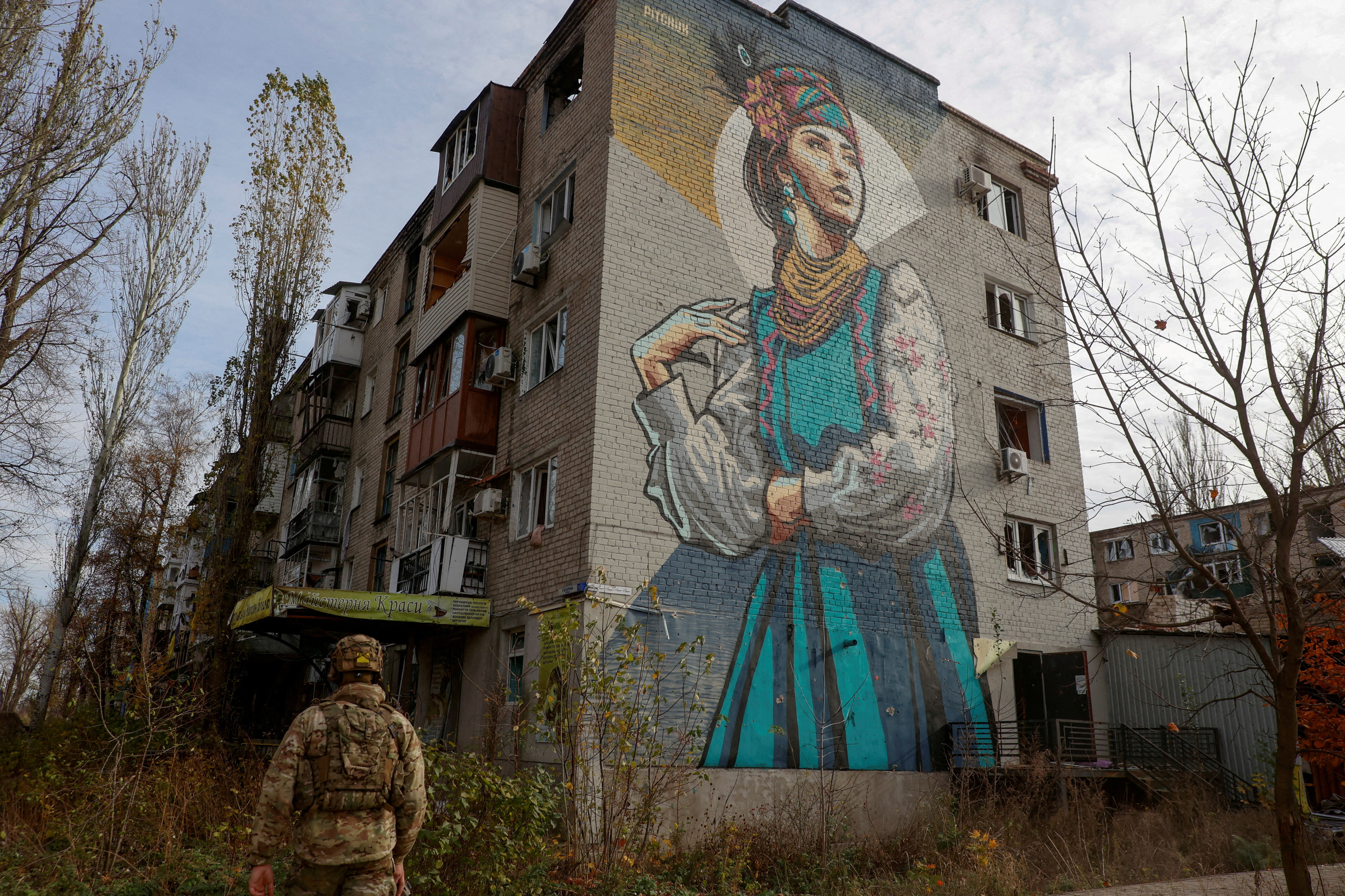 FILE PHOTO: Ukrainian serviceman walks next to a residential building heavily damaged by permanent Russian military strikes in the front line town of Avdiivka