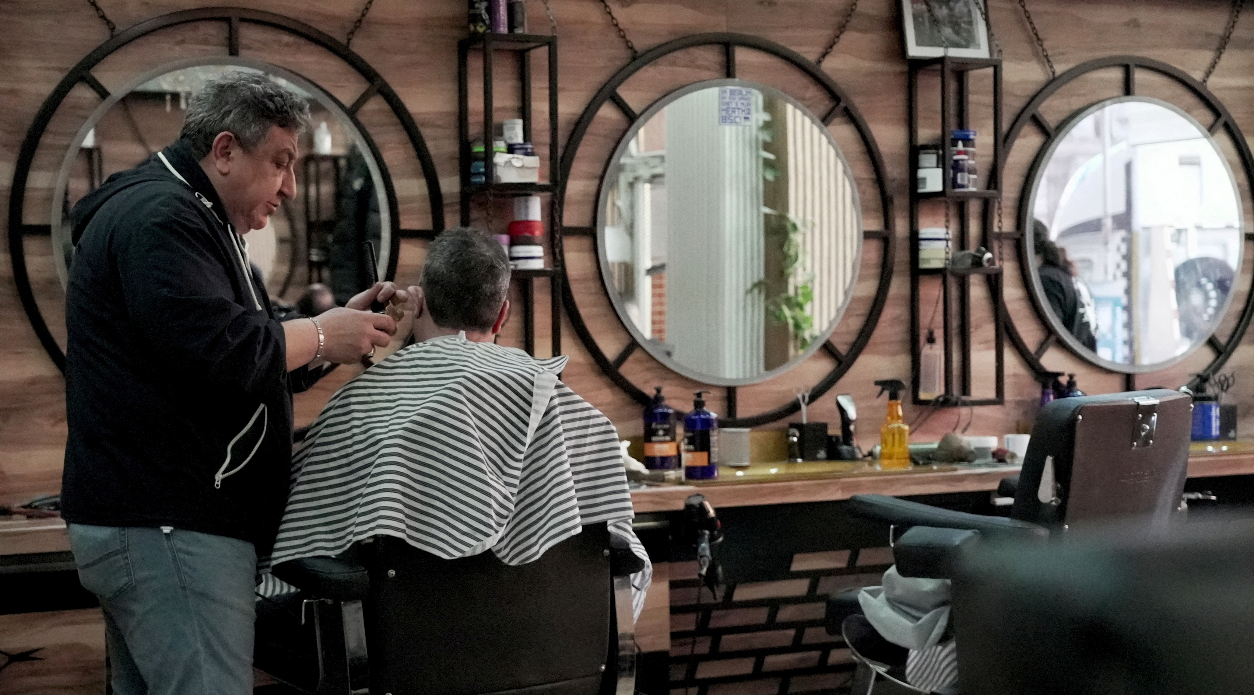 Migrant barber Mohammad Azmouz works at a barber shop in the Neukoelln neighbourhood, in Berlin