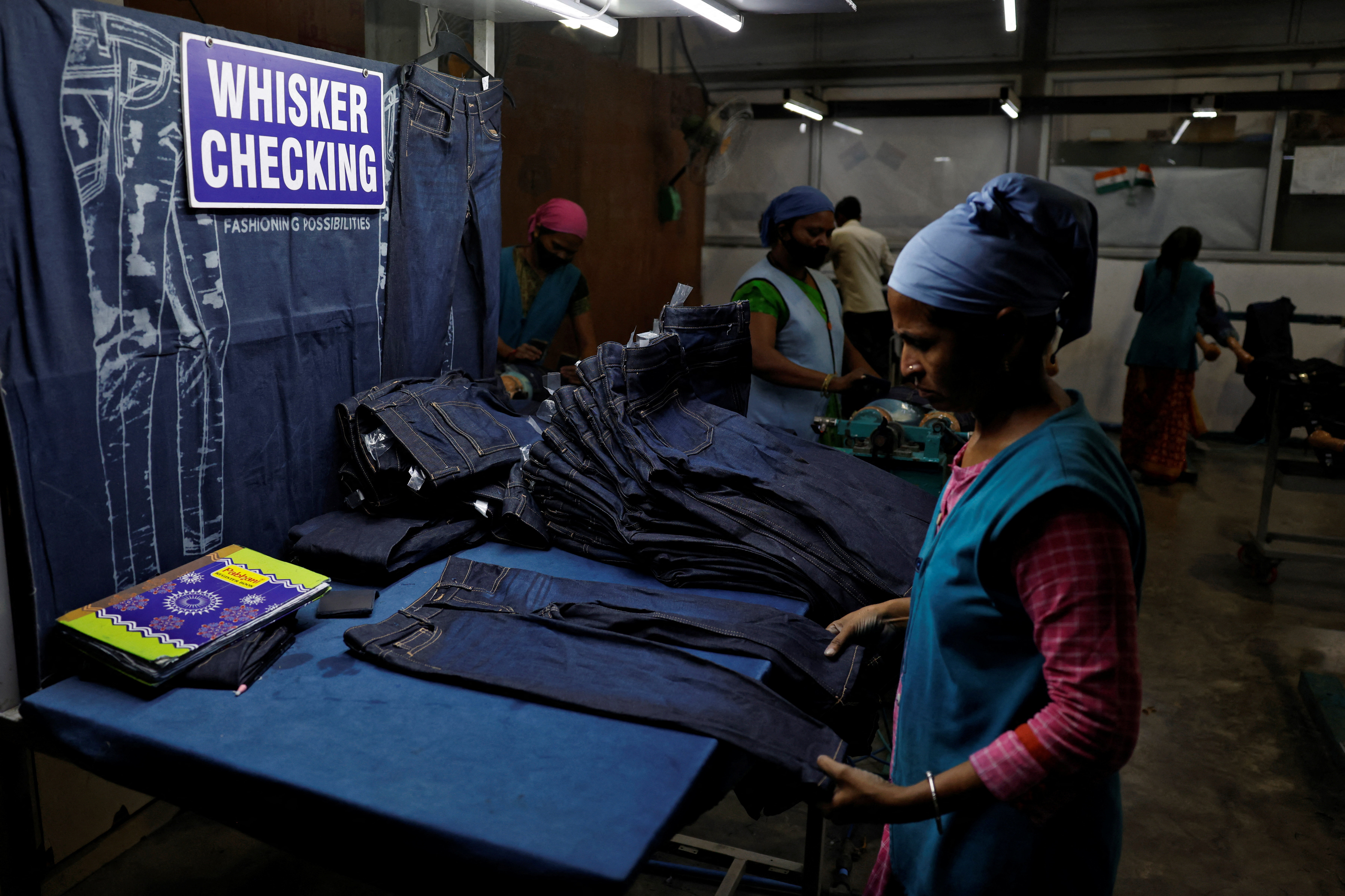 Workers make final checks on jeans pants before packaging in a garment manufacturing unit on the outskirts of Ahmedabad