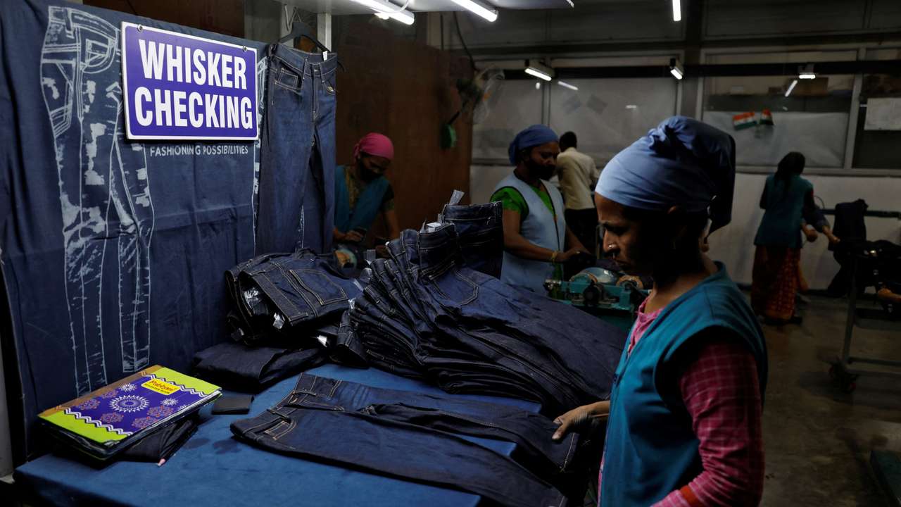 Workers make final checks on jeans pants before packaging in a garment manufacturing unit on the outskirts of Ahmedabad