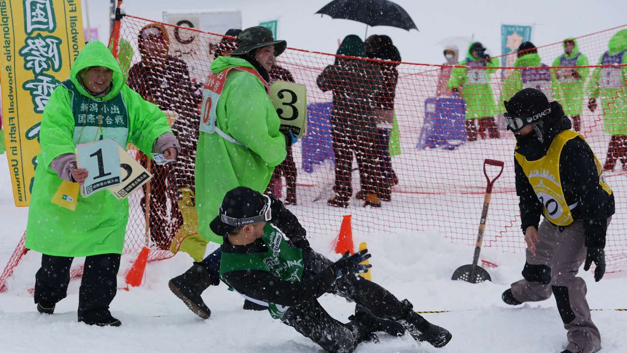 A man falls while throwing a snowball at the 35th Koide International Snowball Fight in Uonuma