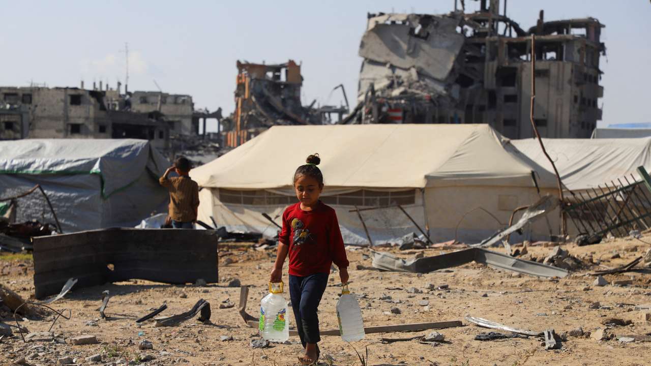 Displaced Palestinian girl carries water containers near tents, amid a ceasefire between Israel and Hamas, in Gaza City