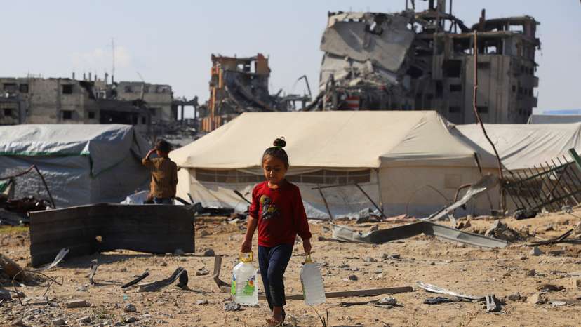 Displaced Palestinian girl carries water containers near tents, amid a ceasefire between Israel and Hamas, in Gaza City