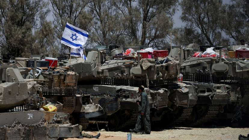 FILE PHOTO: An Israeli soldier walks near military vehicles, amid the ongoing conflict between Israel and the Palestinian Islamist group Hamas, near Israel's border with Gaza in southern Israel