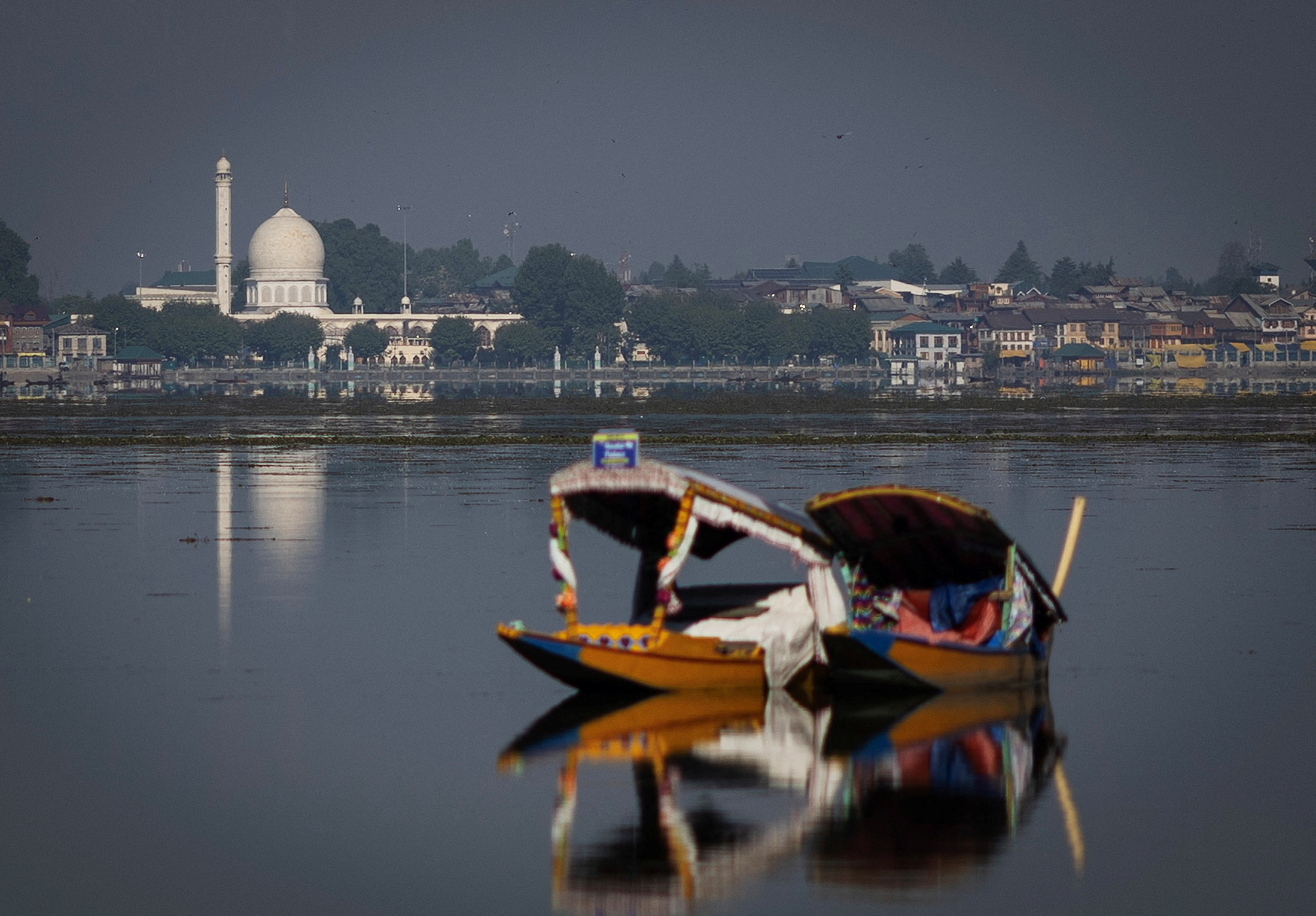 A traditional Shikara boat is seen in the waters of Dal Lake as the Hazratbal shrine is seen in the background in Srinagar