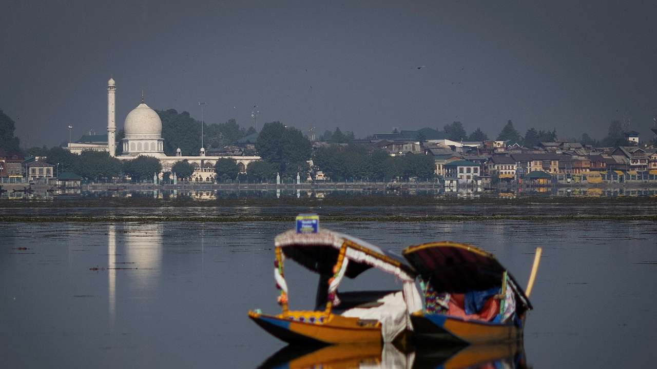A traditional Shikara boat is seen in the waters of Dal Lake as the Hazratbal shrine is seen in the background in Srinagar