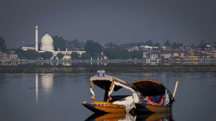 A traditional Shikara boat is seen in the waters of Dal Lake as the Hazratbal shrine is seen in the background in Srinagar