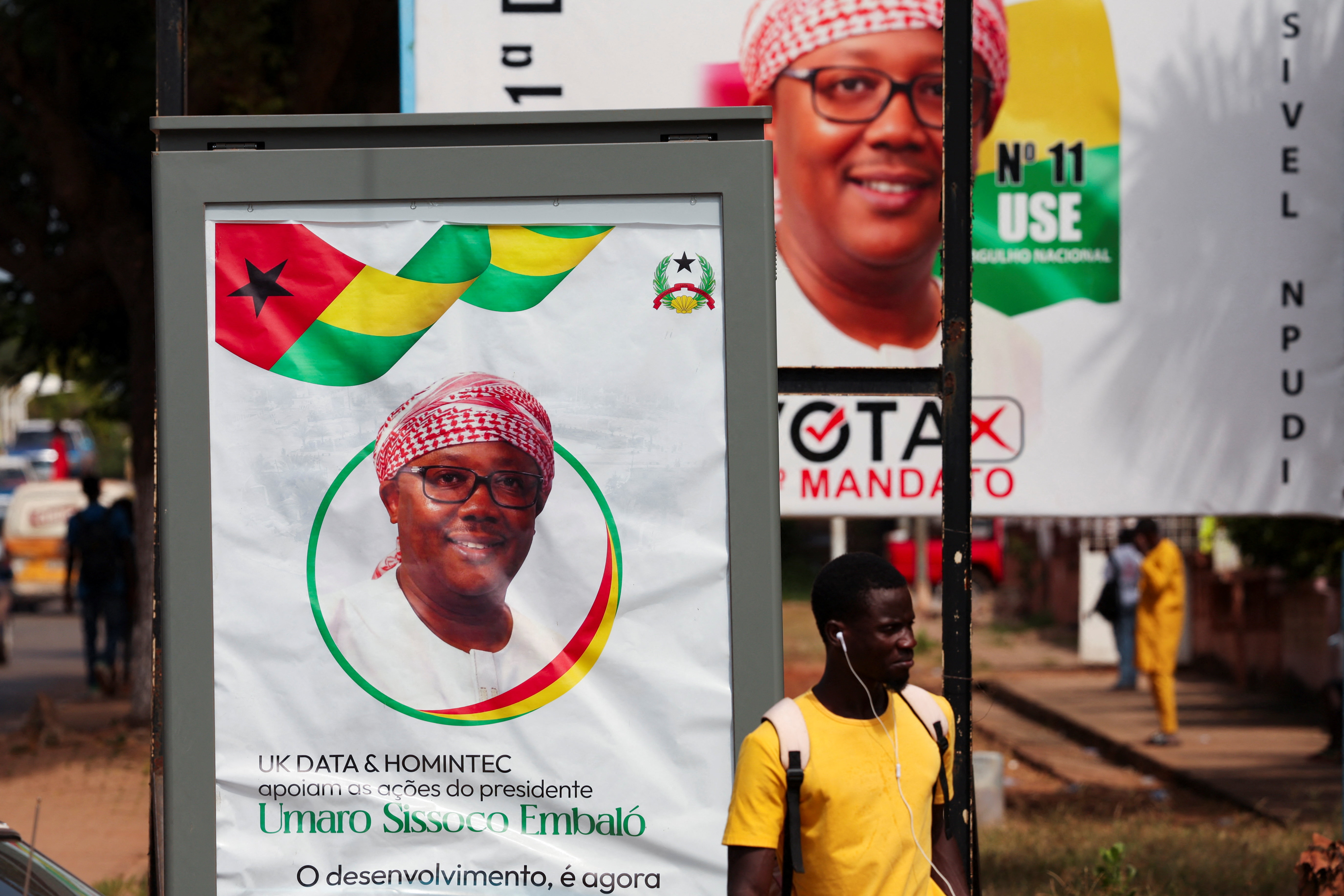 A man stands near campaign billboards of Guinea-Bissau's outgoing President Umaro Sissoco Embalo, ahead of the presidential election in Bissao