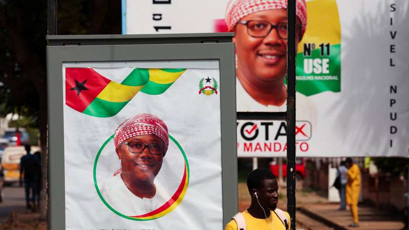 A man stands near campaign billboards of Guinea-Bissau's outgoing President Umaro Sissoco Embalo, ahead of the presidential election in Bissao