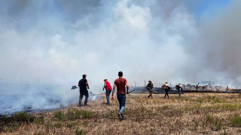 People work to put out fires after Hezbollah launched projectiles at Israel, amid hostilities between Hezbollah and Israeli forces, in the Galilee