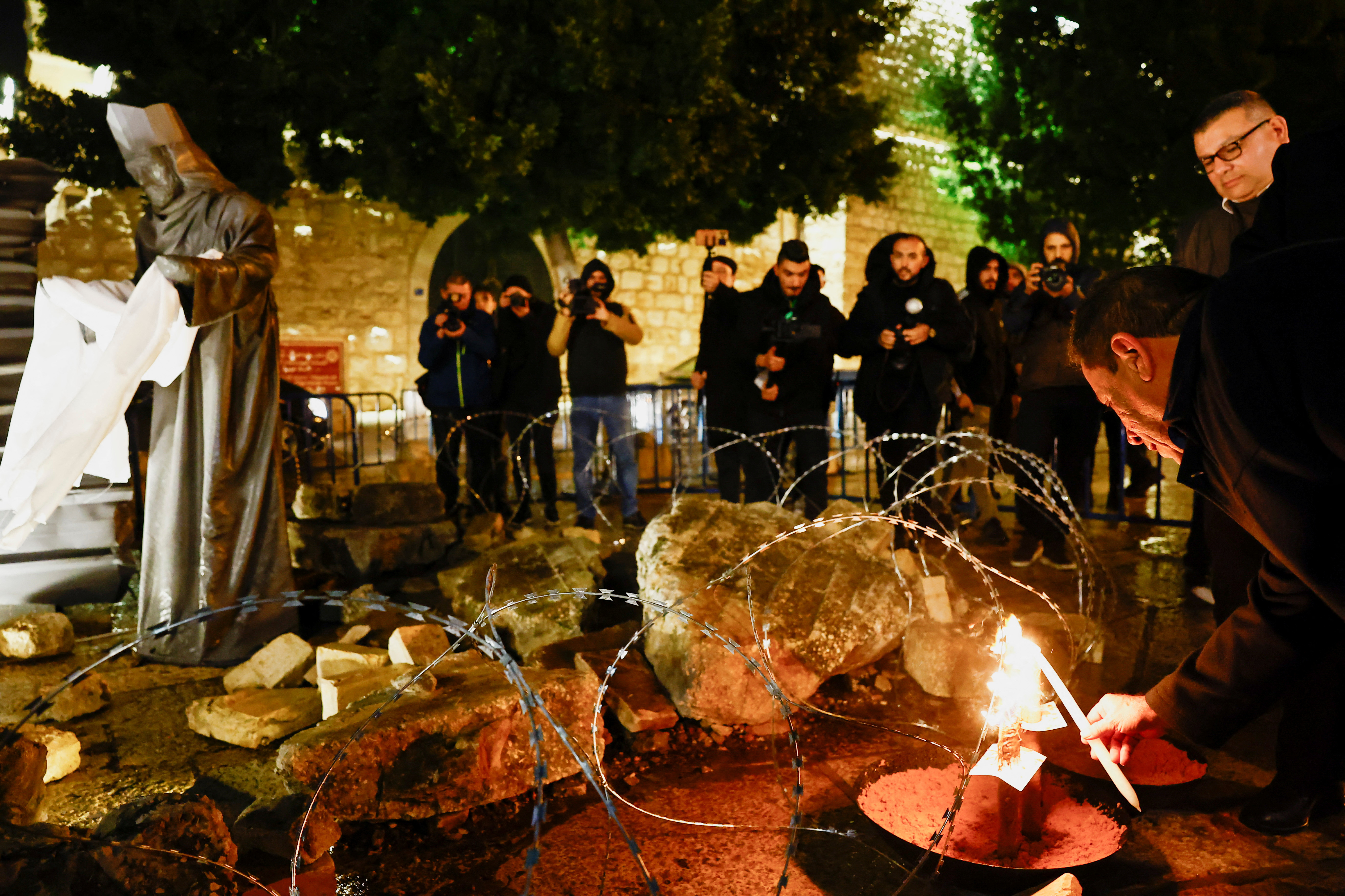 Christmas installation of a grotto with figures standing amid rubble, on Manger Square in Bethlehem