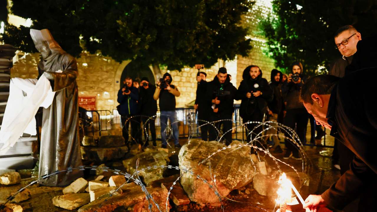 Christmas installation of a grotto with figures standing amid rubble, on Manger Square in Bethlehem