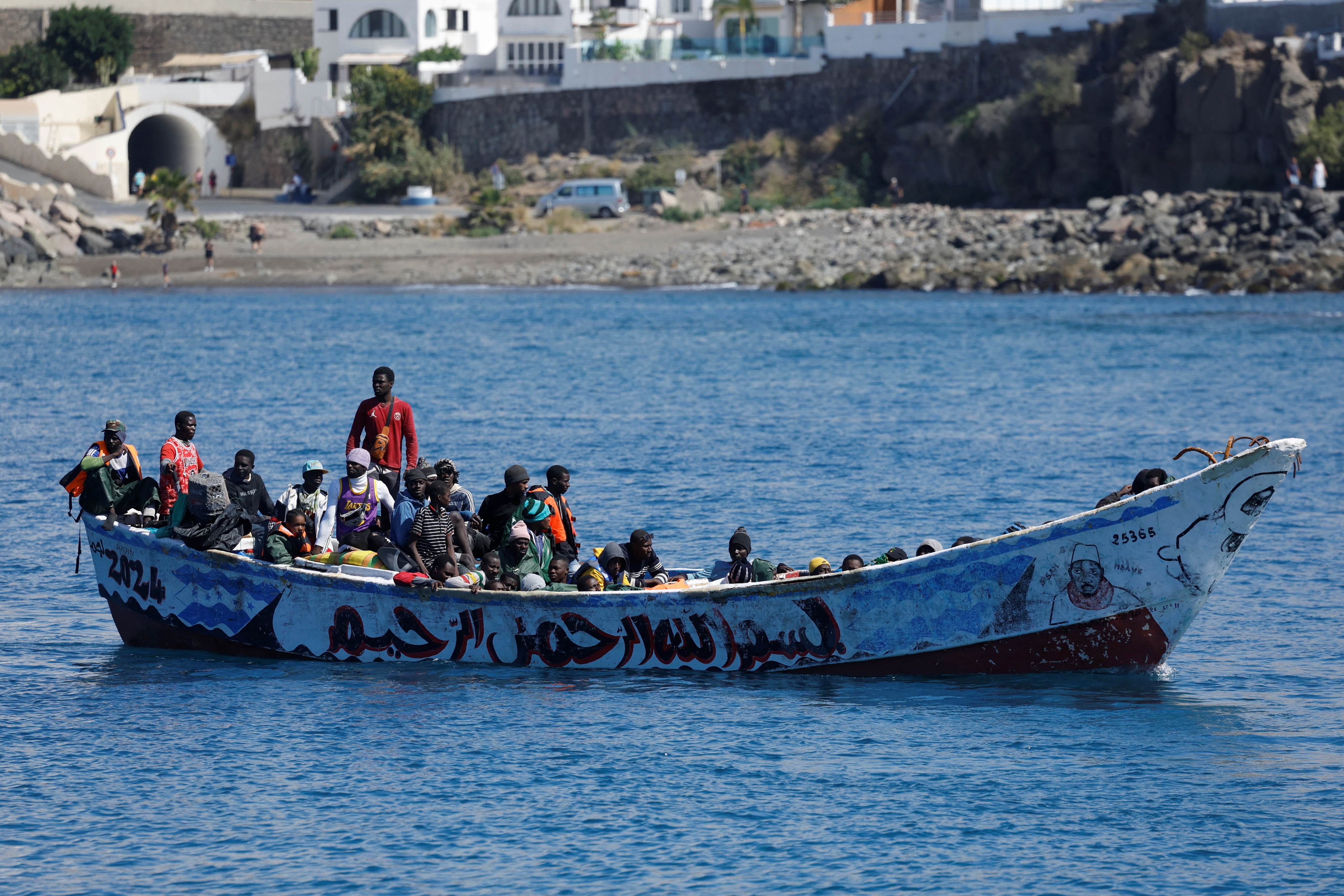 Migrants wait to disembark from a fiber boat in the port of Arguineguin