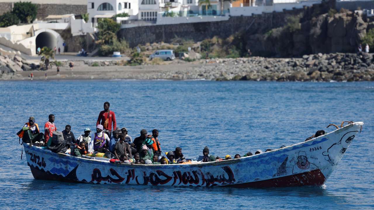 Migrants wait to disembark from a fiber boat in the port of Arguineguin