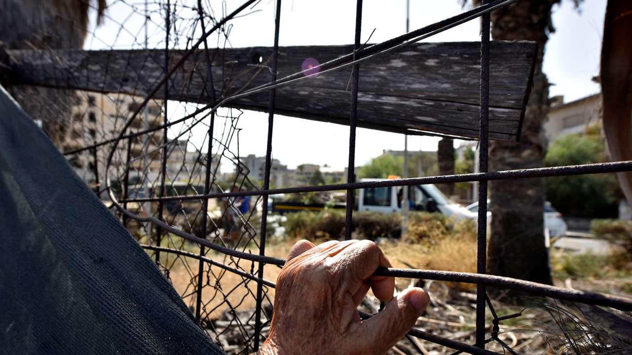 FILE PHOTO: A man holds a fence in the abandoned coastal area of Varosha