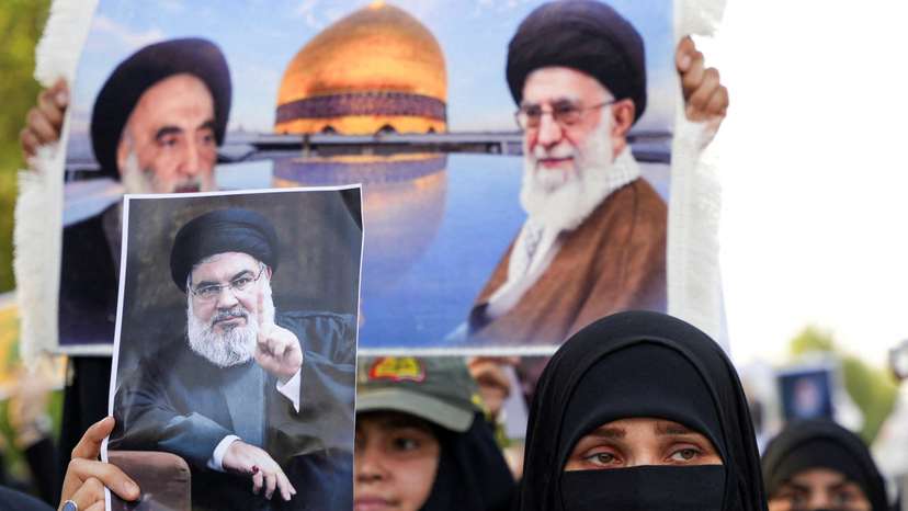 A woman holds a picture of Lebanon's Hezbollah Chief Hassan Nasrallah who was killed by an Israeli airstrike in Beirut, during a symbolic funeral in Basra