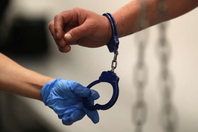 FILE PHOTO: A U.S. Immigration and Customs Enforcement's (ICE) Fugitive Operations Agent takes handcuffs off before booking an immigrant, March 1, 2020. REUTERS/Lucy Nicholson/File Photo