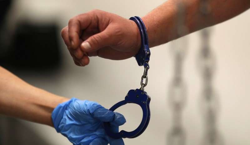 A U.S. Immigration and Customs Enforcement's (ICE) Fugitive Operations Agent takes handcuffs off before booking an immigrant in Los Angeles