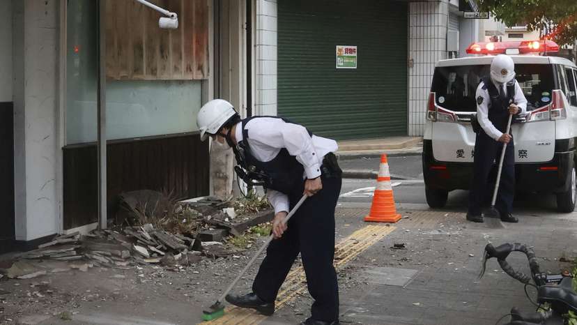Police officers try to remove debris caused by an earthquake in Uwajima, Ehime prefecture, western Japan